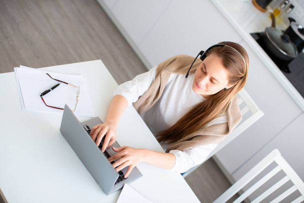 Online work concept. Woman works online in front of a laptop monitor. Filling out tax forms or pays bills. Photo in home interior. - Foto, Imagem