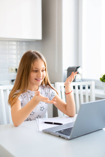 Bilgisayarın başında kulaklıklı bir kız online ders sırasında öğretmeniyle konuşuyor.. - Fotoğraf, Görsel