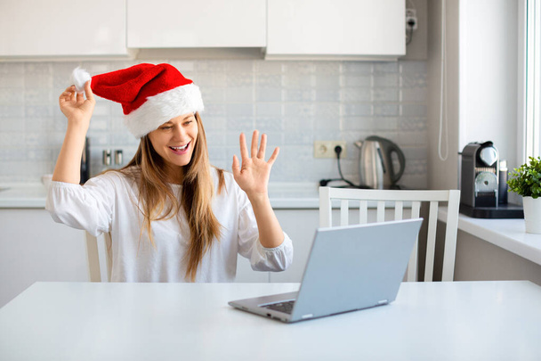 Γυναίκα στο Santa Hat στο σπίτι μπροστά από το laptop οθόνη. - Φωτογραφία, εικόνα