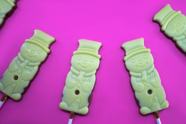Смішні шоколадні цукерки сніговика на кольоровому фоні
 - Фото, зображення
