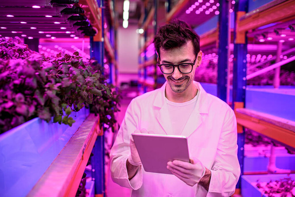 Worker with tablet on aquaponic farm, sustainable business and artificial lighting. - Fotoğraf, Görsel