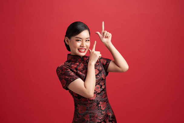 Ασιάτισσα Κινέζα με παραδοσιακό φόρεμα σε κόκκινο φόντο. Κινέζικο φεστιβάλ νέου έτους. - Φωτογραφία, εικόνα