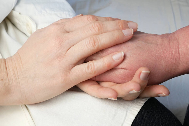 Handen van de arts die de handen van de patiënt vasthouden als uitdrukking van zorg en ondersteuning, close-up - Foto, afbeelding