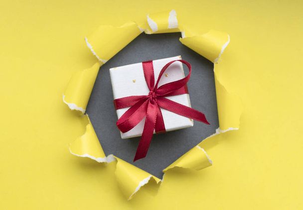 gift box with red ribbon bow, isolated on yellow - Photo, Image