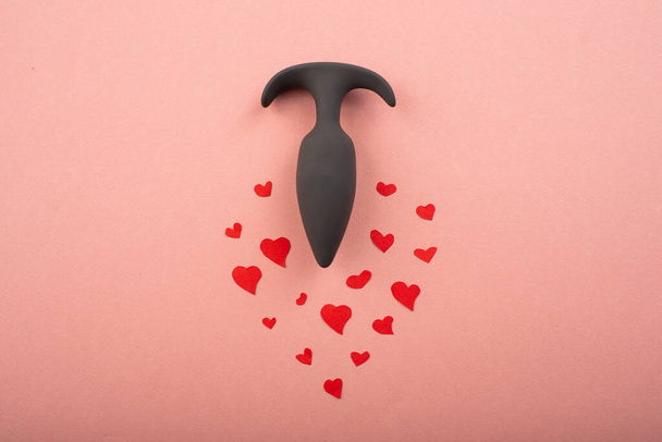 Butt plug and hearts on a pink background. Love symbol for February 14. Copy space - Foto, afbeelding