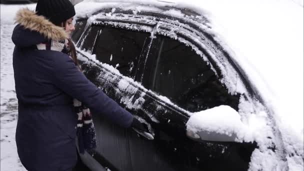Una donna cerca di aprire la macchina con il gelo. La porta è congelata. Inverno - Filmati, video