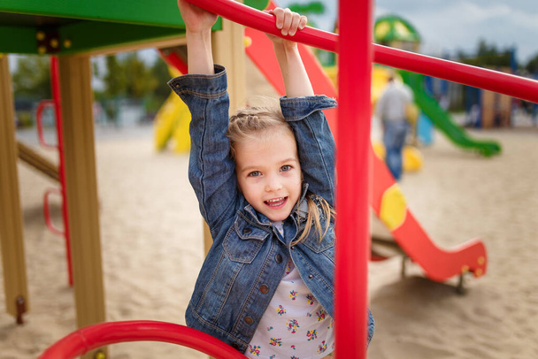 Close up portrait of little girl on playground. Happy smiling joyful kid, true emotion, carefree childhood concept. - Photo, Image