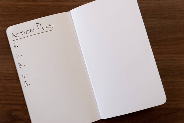 Σημειωματάριο σελίδα που φέρει την ένδειξη "Σχέδιο δράσης" με μαύρο μελάνι σε λευκό χαρτί, και αριθμημένη λίστα. - Φωτογραφία, εικόνα