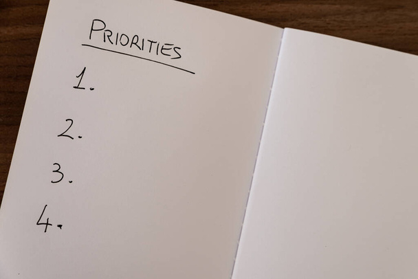 Сторінка зошита з позначкою "Пріоритети" у чорному чорнилі на білому папері та нумерованим списком
. - Фото, зображення