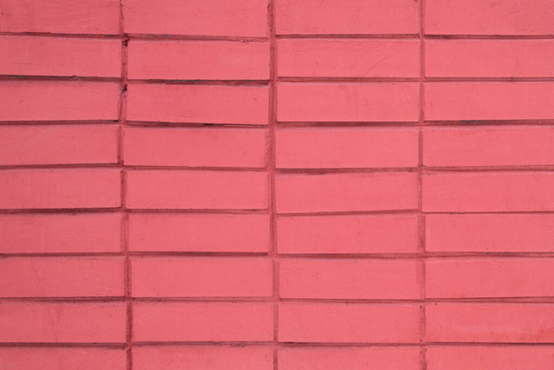 the old wall is covered with tiles with imitation bricks, painted in rich scarlet color - Foto, Imagem