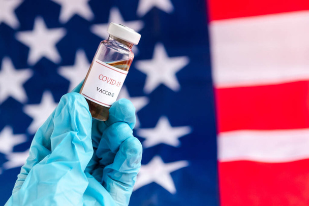 Les mains du médecin portent des gants portant le vaccin contre le coronavirus (COVID-19) sur le drapeau des États-Unis d'Amérique fond, États-Unis Vaccination - Photo, image