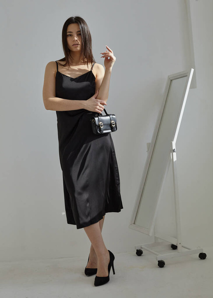beautiful brunette in a silk spring dress in black on a light background - 写真・画像