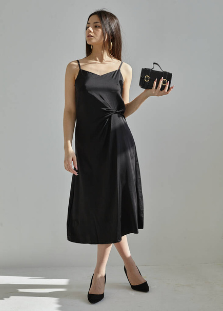 beautiful brunette in a silk spring dress in black on a light background - Fotoğraf, Görsel