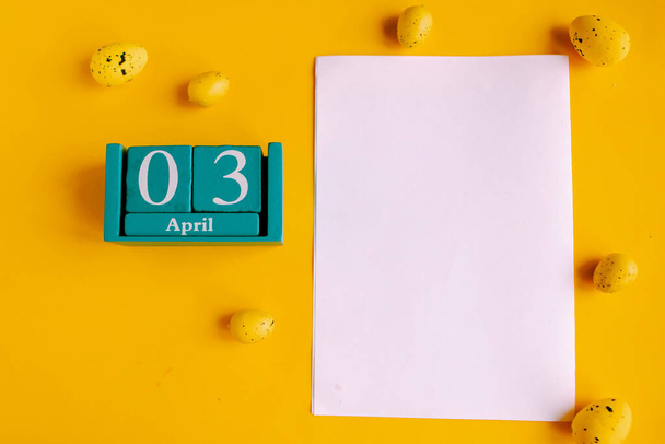 April 3. Blue cube calendar with month date and white mockup blank on yellow background. - Photo, Image