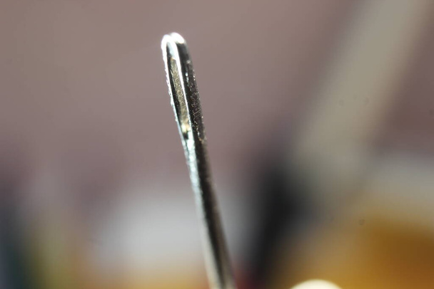 Macro photograph of sewing needle. Small needle with empty eyelet, isolated over the black background. - Photo, Image