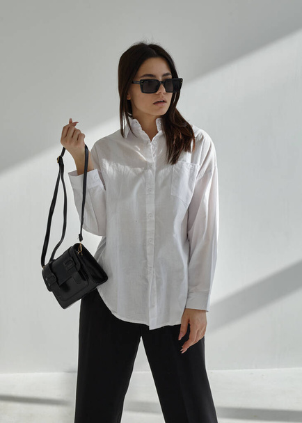 portrait of a beautiful brunette woman in sunglasses and white shirt - 写真・画像