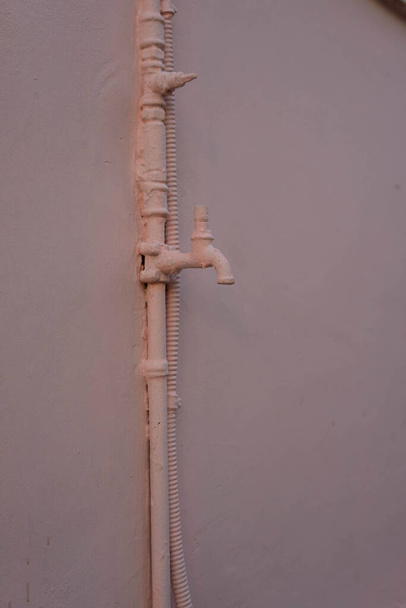 Wasserhahn und Rohr mit rosa Wand - Foto, Bild