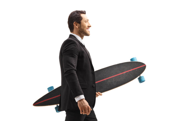Young businessman in a suit walking and carrying a longboard isolated on white background - Foto, imagen