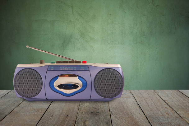 Синій радіокасетний магнітофон з антеною на дерев'яній підлозі і старим фоном цементної стіни
. - Фото, зображення