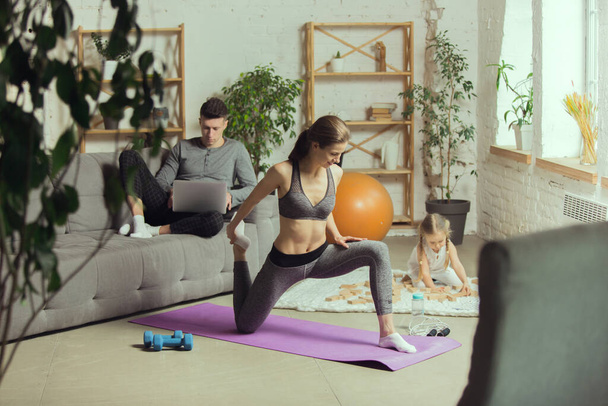 Young woman exercising fitness, aerobic, yoga at home, sporty lifestyle. Getting active during lockdown, quarantine. Home gym. - Fotoğraf, Görsel