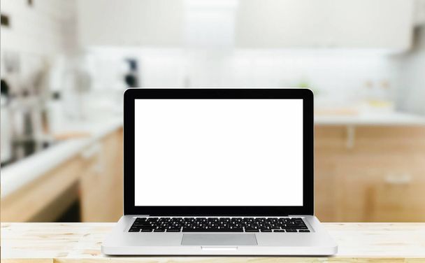 Moderní počítač, notebook s prázdnou obrazovkou na dřevěné desce stolu na rozmazaném kuchyňském pozadí - Fotografie, Obrázek