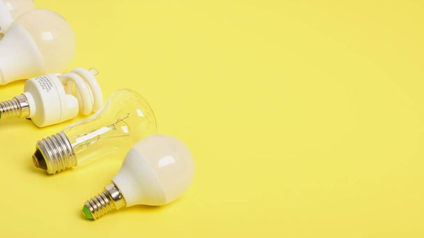 several different bulbs on a yellow background, copy space, trend color, broken and burned out bulbs for recycling - Фото, изображение