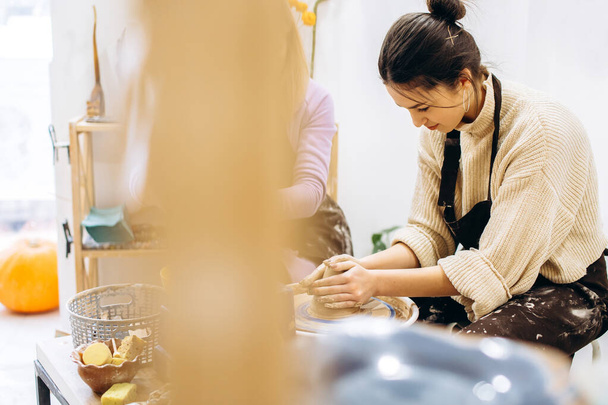 Творческий процесс создания керамики матерью и дочерьми. Руки женщины в мастерской по керамике. - Фото, изображение