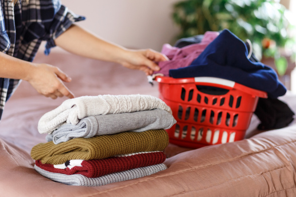 женщина руки складывая одежду в спальне, взяв из красной прачечной - Фото, изображение