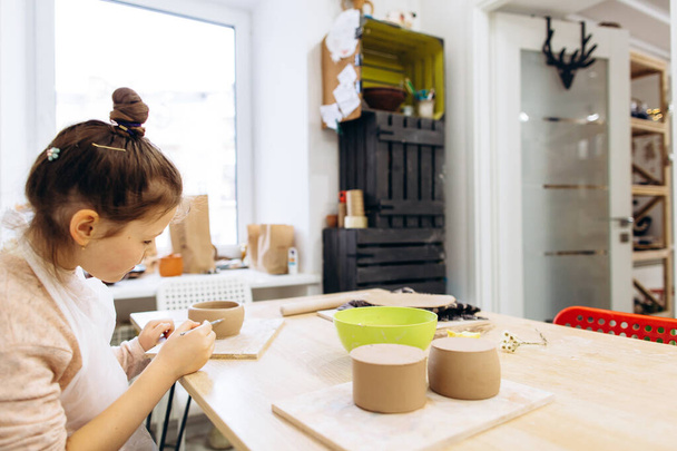 Две сестры украсить глиняную тарелку перед стрельбой в керамической студии, дети с кисточками и керамики - Фото, изображение