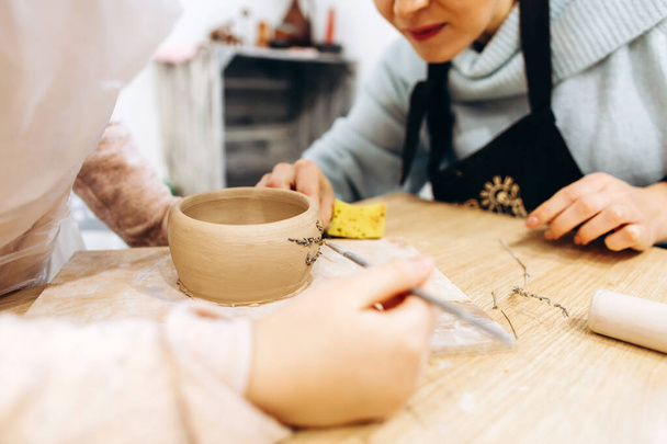 Madre e figlia decorano un piatto di argilla prima di cuocersi in uno studio di ceramica, decorano un piatto con rami di lavanda. - Foto, immagini
