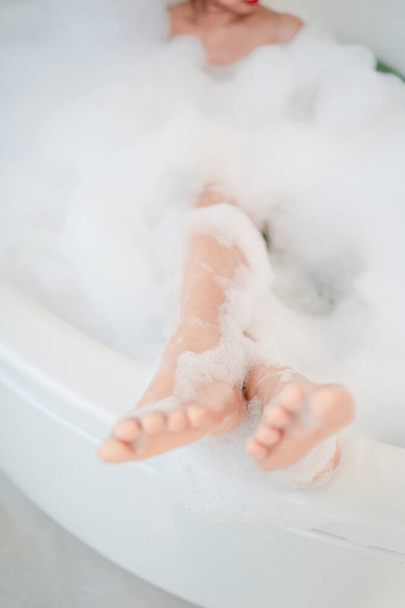 Woman's feet in the bath. She is taking a shower in the bathroom. - Fotografie, Obrázek