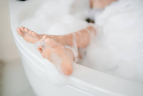 Kobiece stopy bierze kąpiel w wannie z relaksem.  - Zdjęcie, obraz
