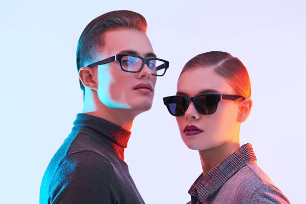 Attractive young man and beautiful young woman  are posing together in stylish glasses. Optics style. Fashion studio shot.  - Φωτογραφία, εικόνα