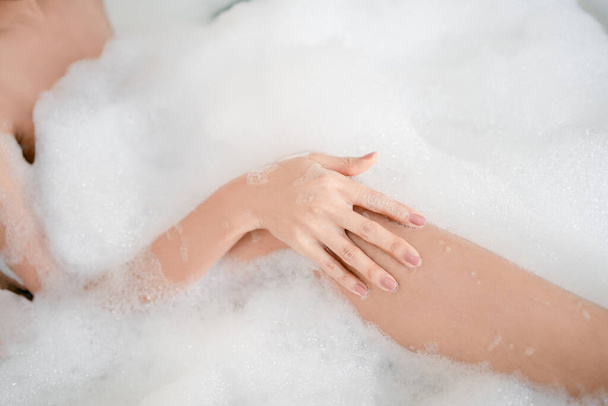 Krásná žena nohy ve vaně s mýdlovými bublinkami. Lázně pro péči o pleť. - Fotografie, Obrázek