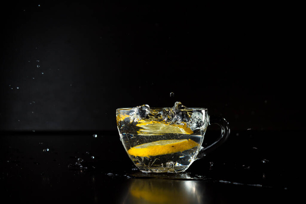water splashes. freezing motion. frozen alcohol spray. a slice of lemon fell into a cup of water. stopped action. menu design. side view. advertising poster - 写真・画像