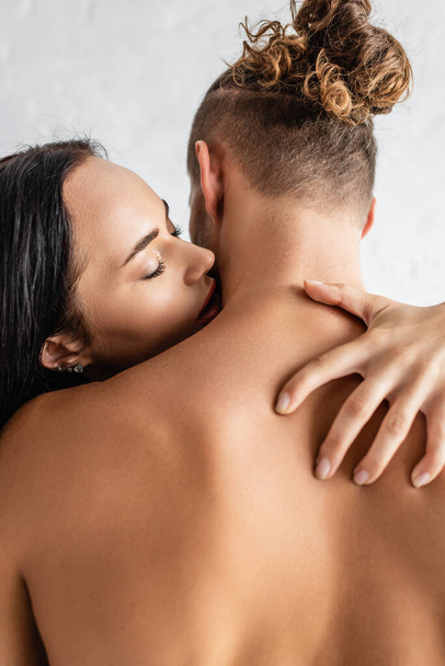 Young woman kissing shirtless man at home  - Photo, Image