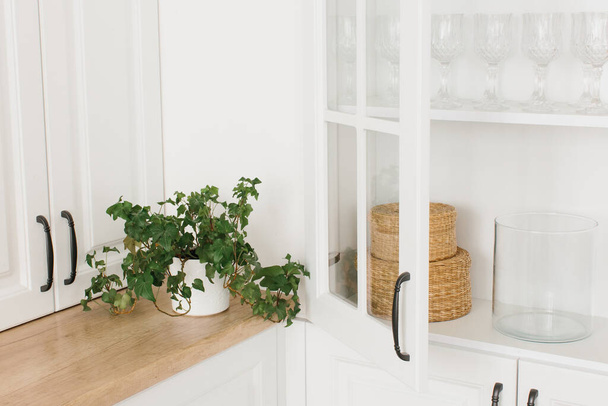 Ανοιγμένο λευκό γυάλινο ντουλάπι με καθαρά πιάτα και διακόσμηση. Οργάνωση της αποθήκευσης στην κουζίνα. - Φωτογραφία, εικόνα