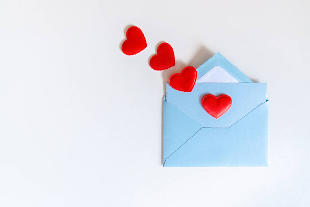 Fliegende rote Herzen aus Liebesbriefen in blauem Umschlag auf weißem Hintergrund. Liebesbrief mit Herz und Kopierraum. Dankbarkeit gegenüber Ärzten und Pflegekräften. Valentinstag, Mutter, Grüße zum Frauentag - Foto, Bild