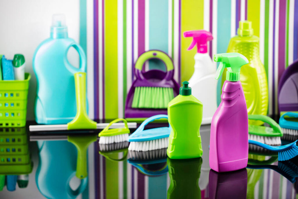 Házi és irodai takarítás téma. Színes készlet palack, klinikai folyadékok és színes tisztító készlet a háttérben formájában színes csíkok. - Fotó, kép