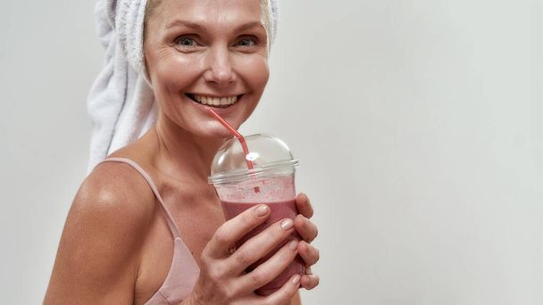 Portrait of middle aged caucasian woman holding smoothie - Foto, Imagen