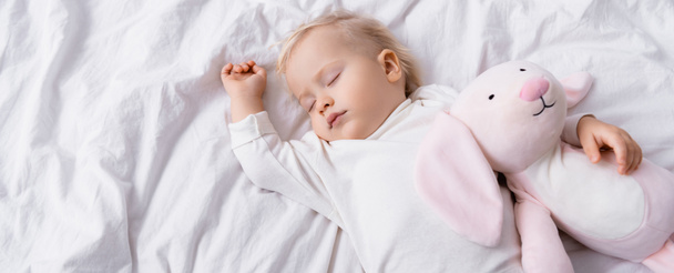 vista aérea de un niño pequeño durmiendo con un conejo de juguete, pancarta - Foto, Imagen