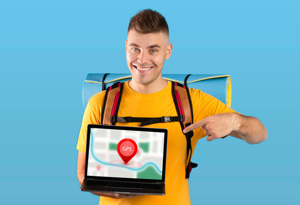 Турист показывает ноутбук с навигационной картой на синем фоне - Фото, изображение