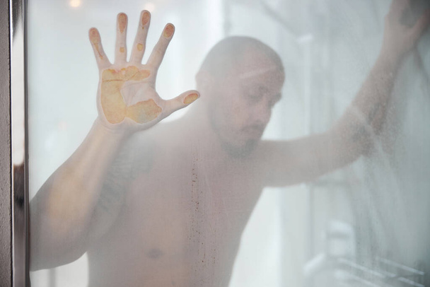 Triste hombre en una ducha mirando hacia abajo - Foto, Imagen