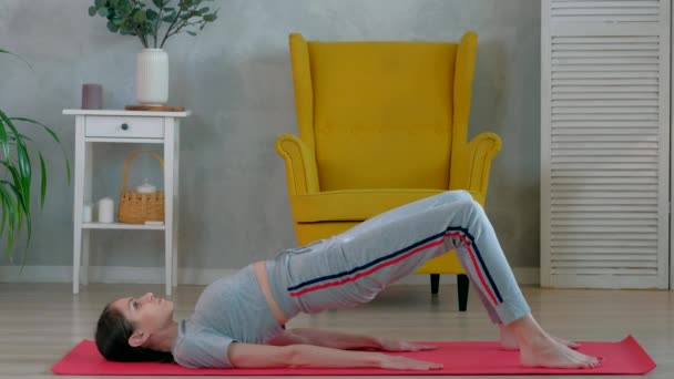 Brunette Nainen tekee jooga harjoituksia aamulla kotona. - Materiaali, video
