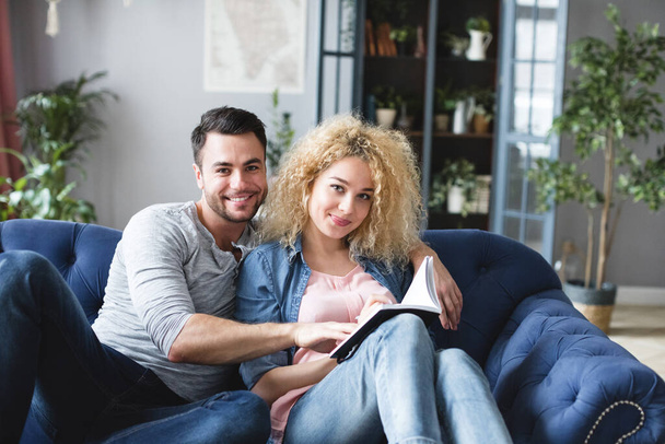 Young beautiful couple with notepad make plans in the home interior sitting on the couch. Domestic life. - Fotoğraf, Görsel