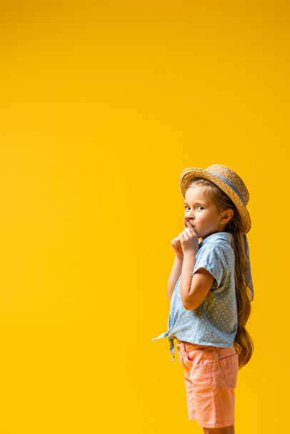 niño en sombrero de paja que muestra signo de silencio aislado en amarillo - Foto, imagen