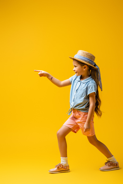 volle Länge des glücklichen Kindes mit temporärer Tätowierung auf der Hand, die mit dem Finger auf gelb zeigt - Foto, Bild