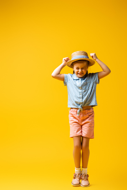 longitud completa del niño excitado con los puños cerrados en amarillo - Foto, Imagen
