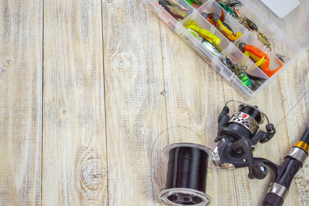 Fishing tackle, many colorful baits with a fishing rod on a wooden pier. Selective focus - Photo, Image