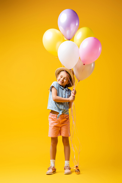 teljes hossza boldog gyerek szalma kalap gazdaság lufik sárga - Fotó, kép